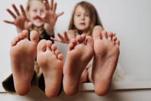 Brother and sister holding bare feet close up to the camera.